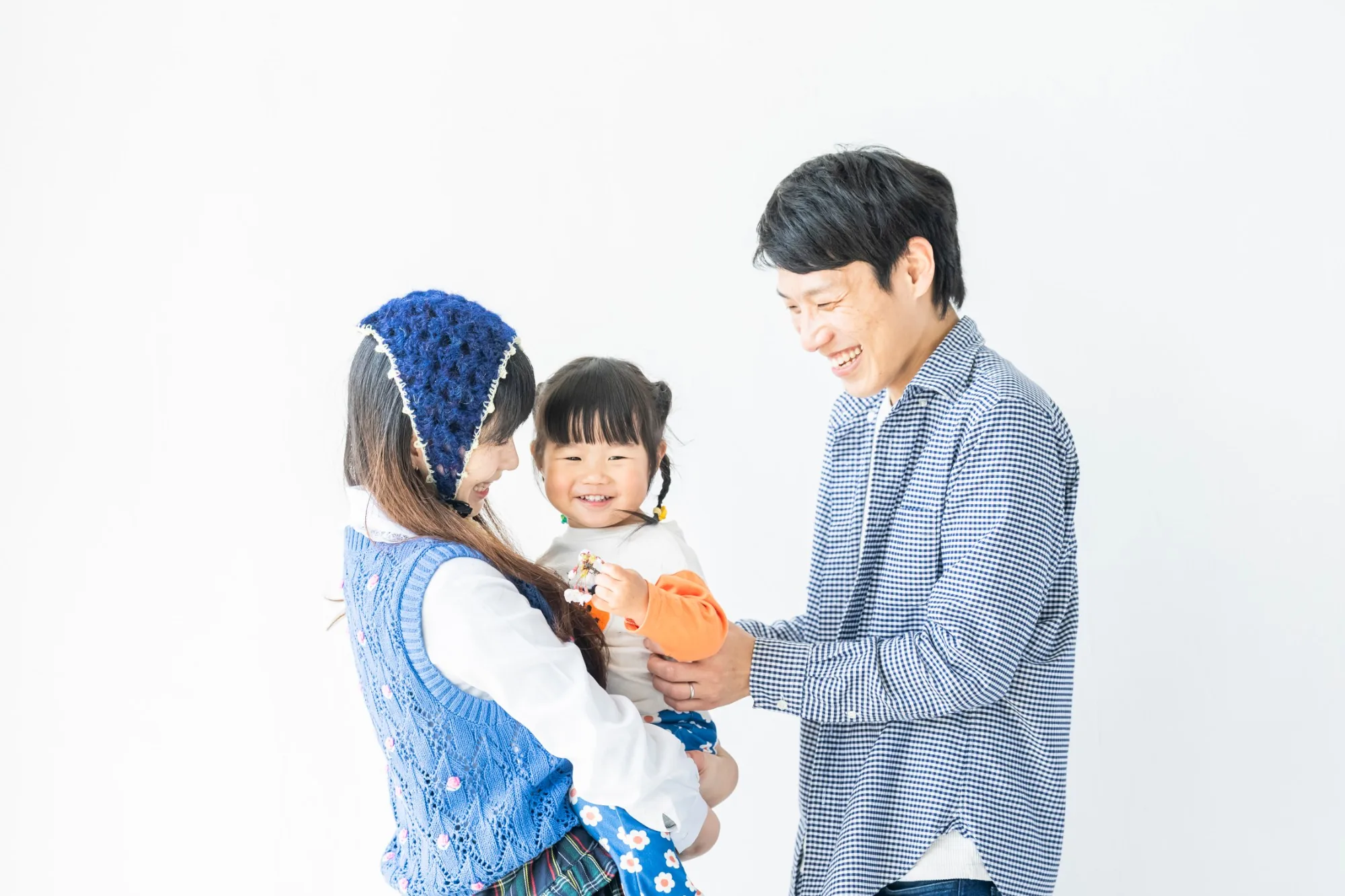 白い背景の前で、両親と一緒に遊ぶ小さな女の子