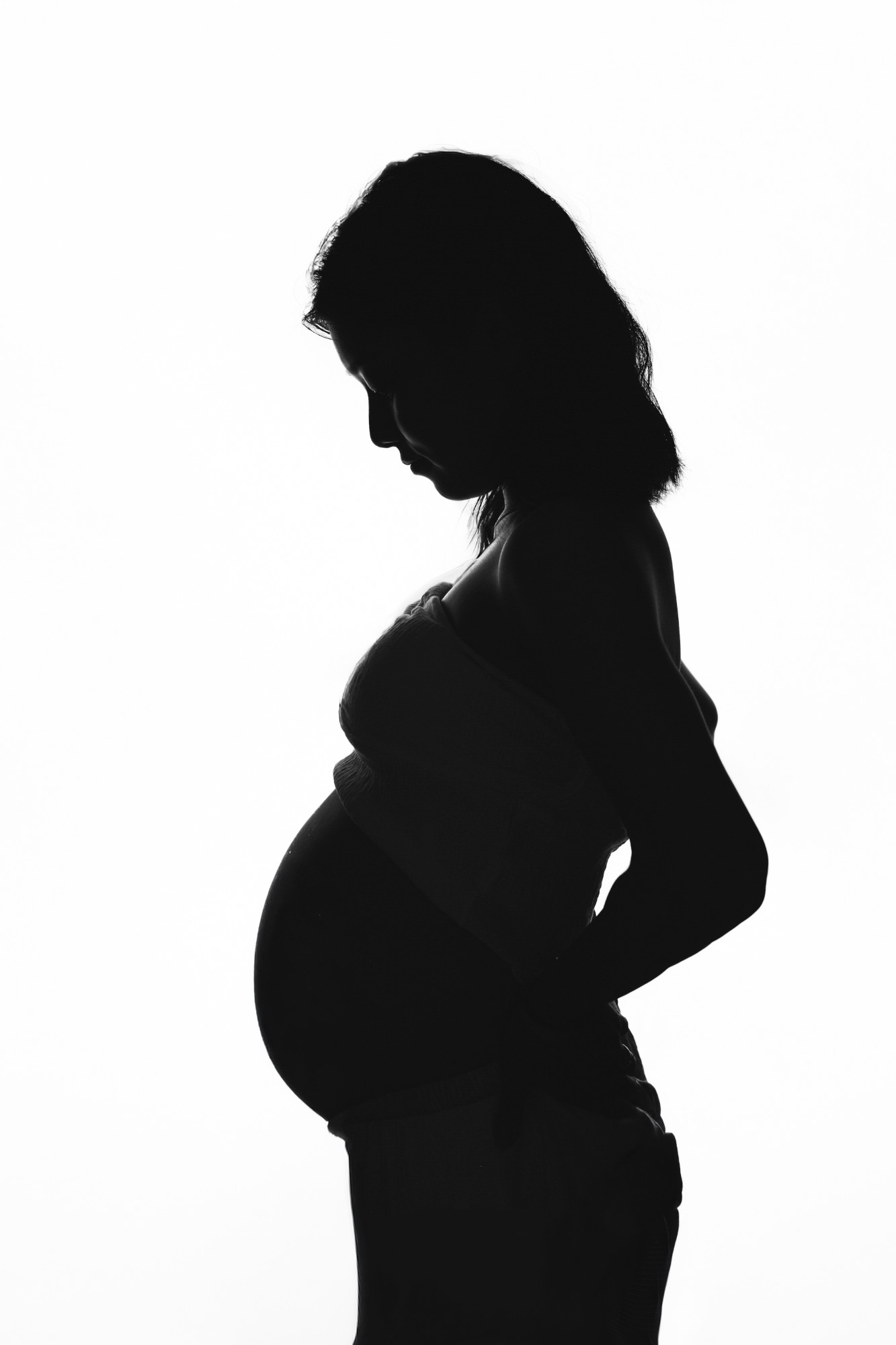 横向きのシルエットで浮かび上がる、妊娠中の女性