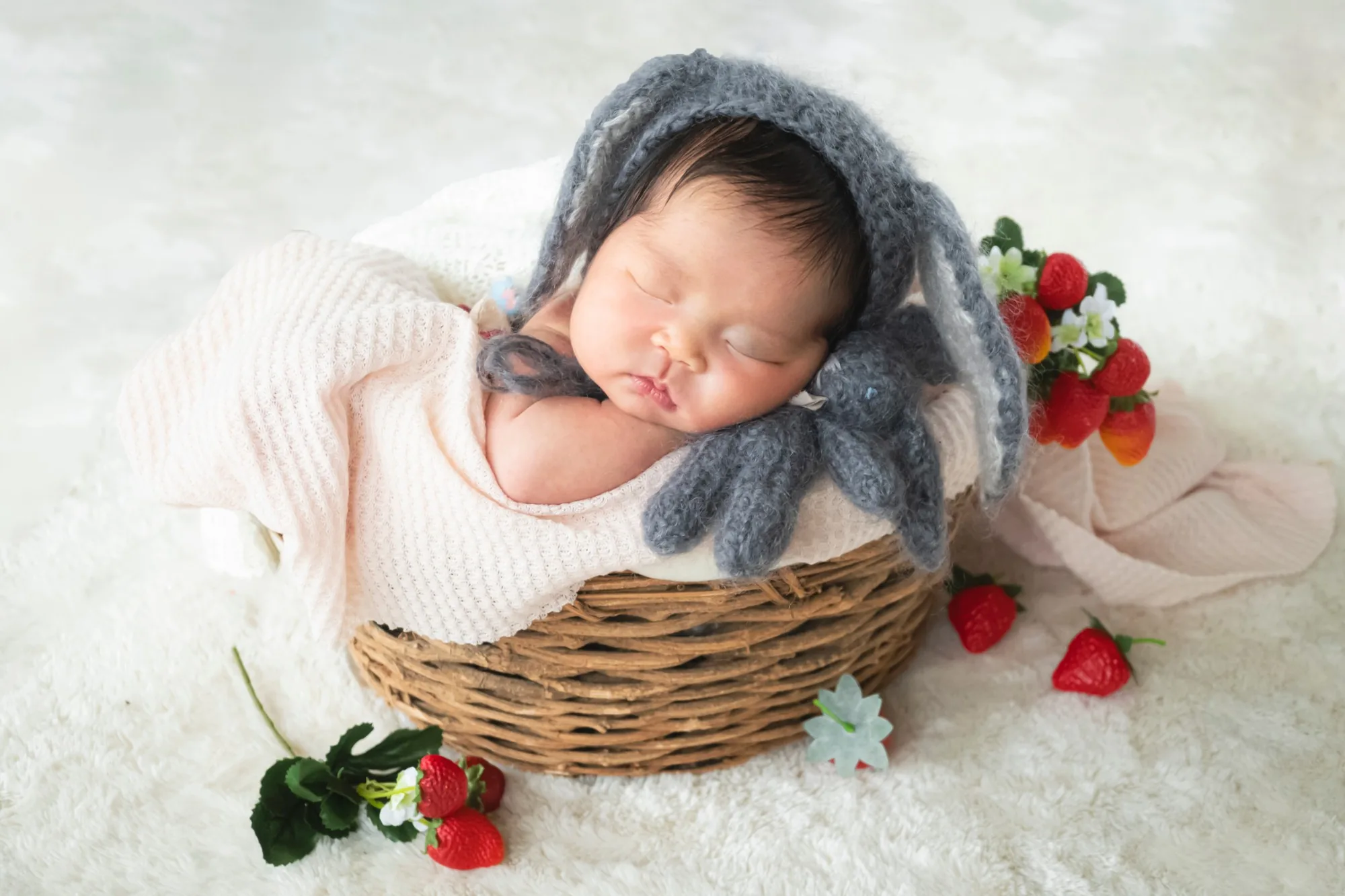 いちごのそばの籠の中で眠る新生児