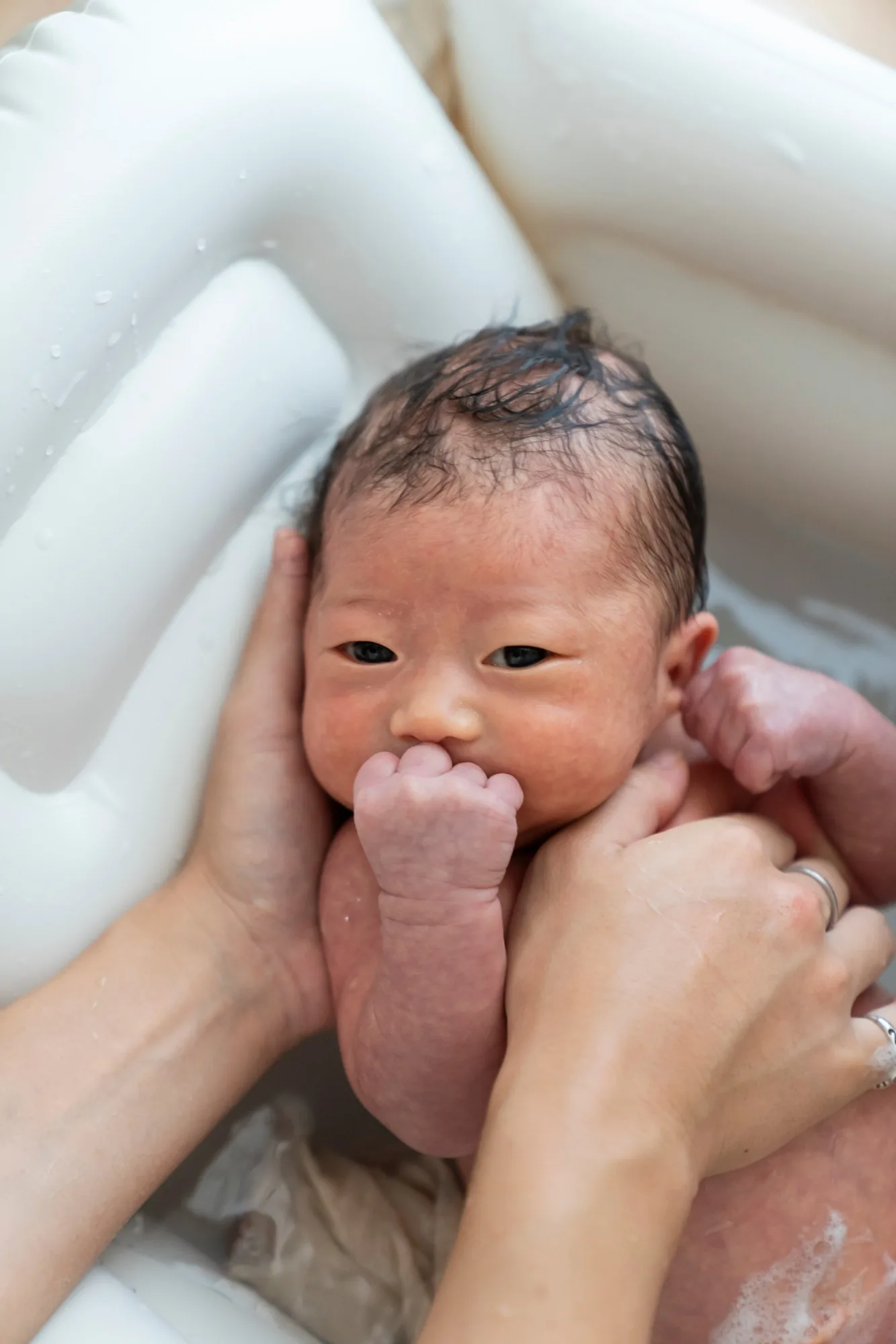 沐浴中、こちらを見つめる新生児