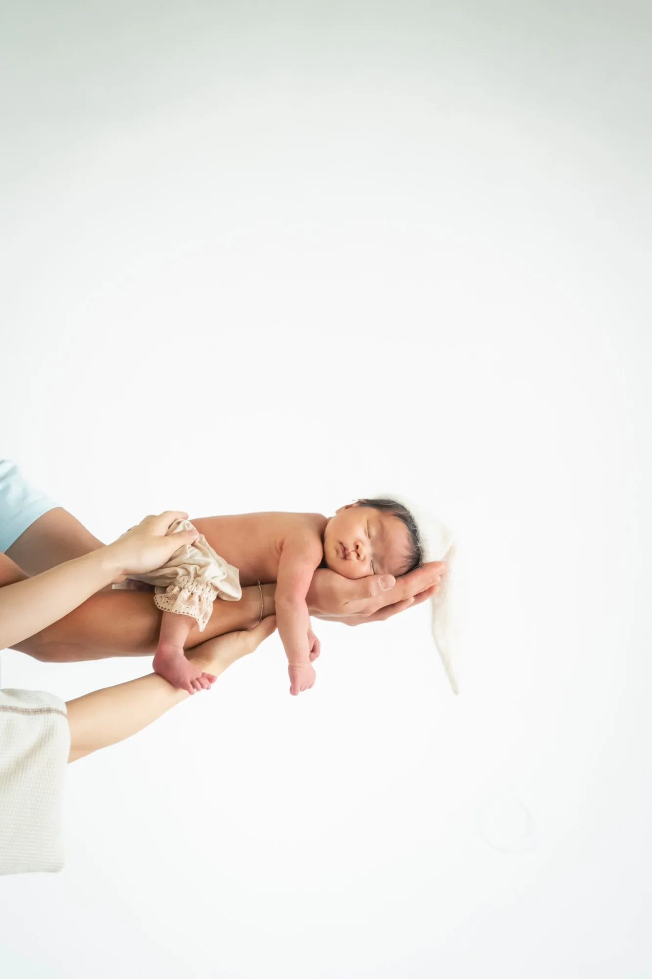 母親の腕に抱かれて眠る新生児