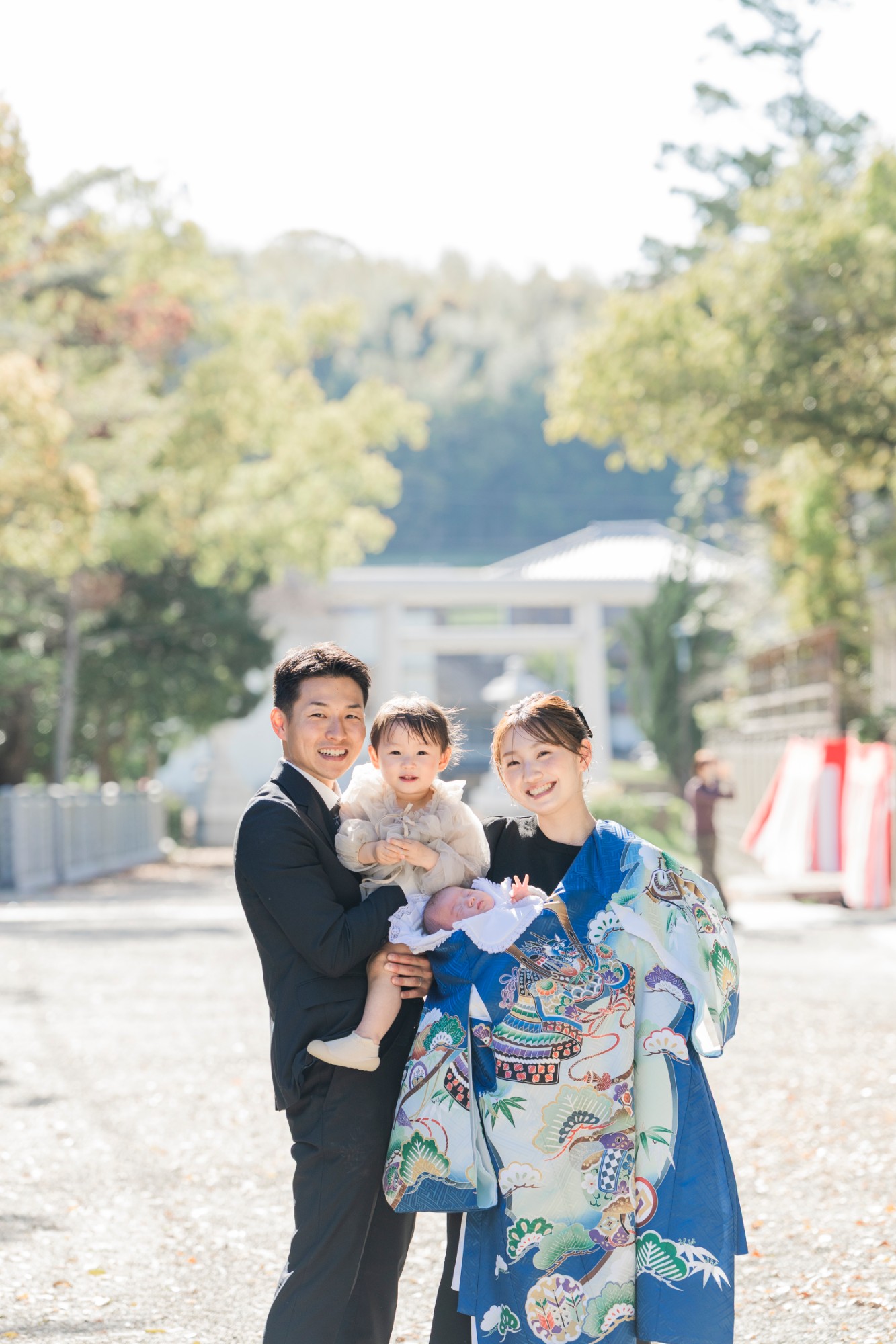神社の参道で、赤ちゃんと兄を抱いて微笑む家族