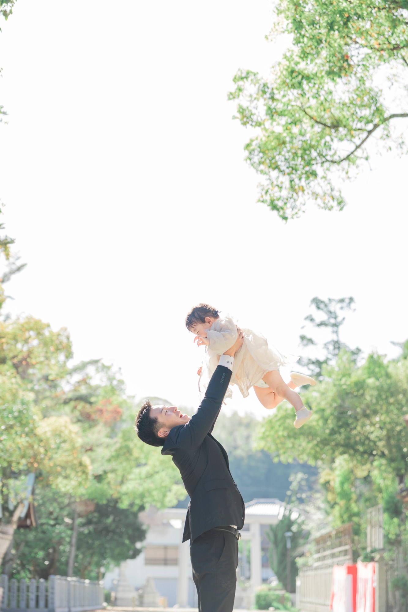 屋外で、父親が子どもを高く抱き上げる瞬間