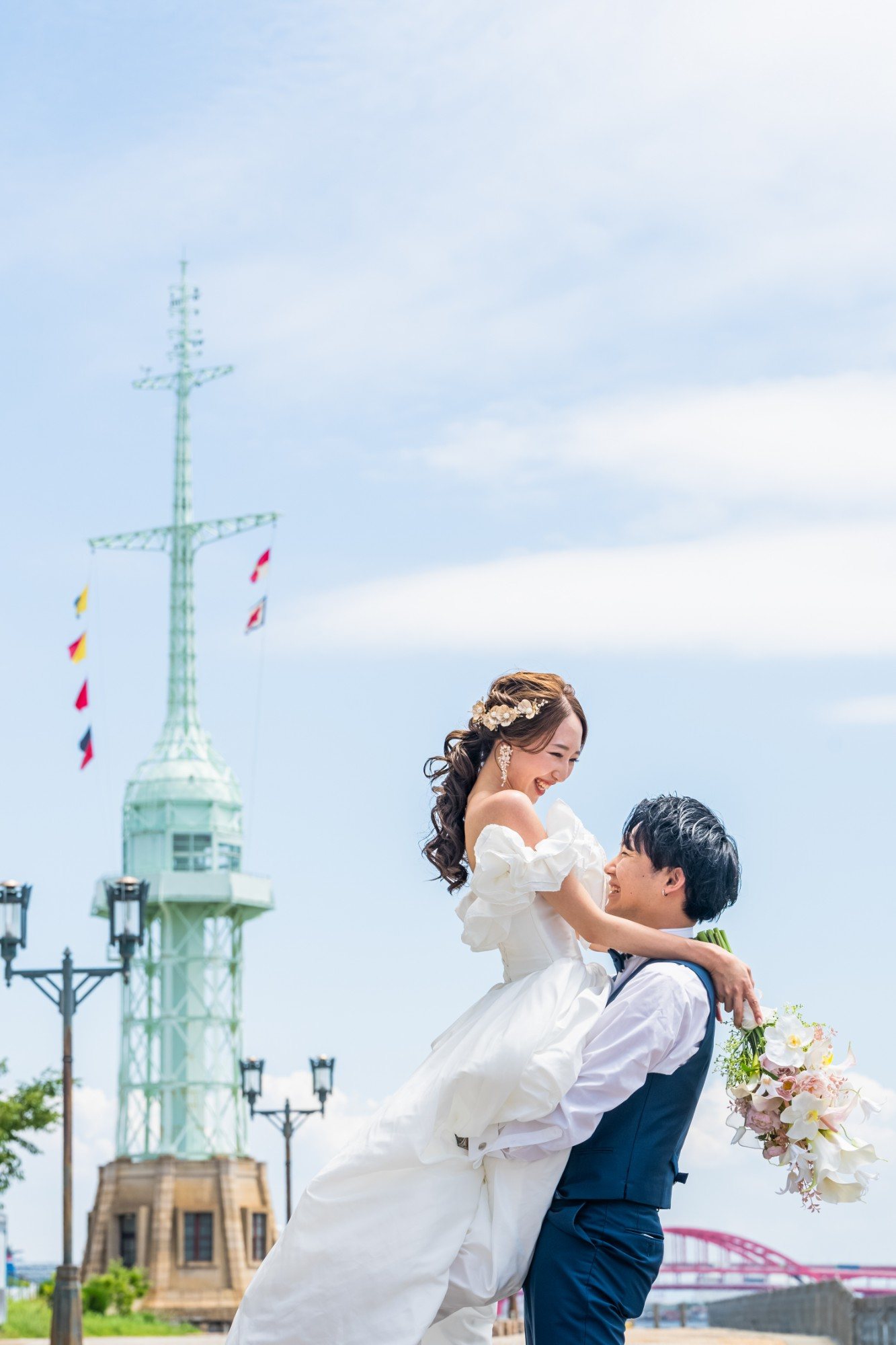 灯台を背景に、新郎に抱き上げられる花嫁