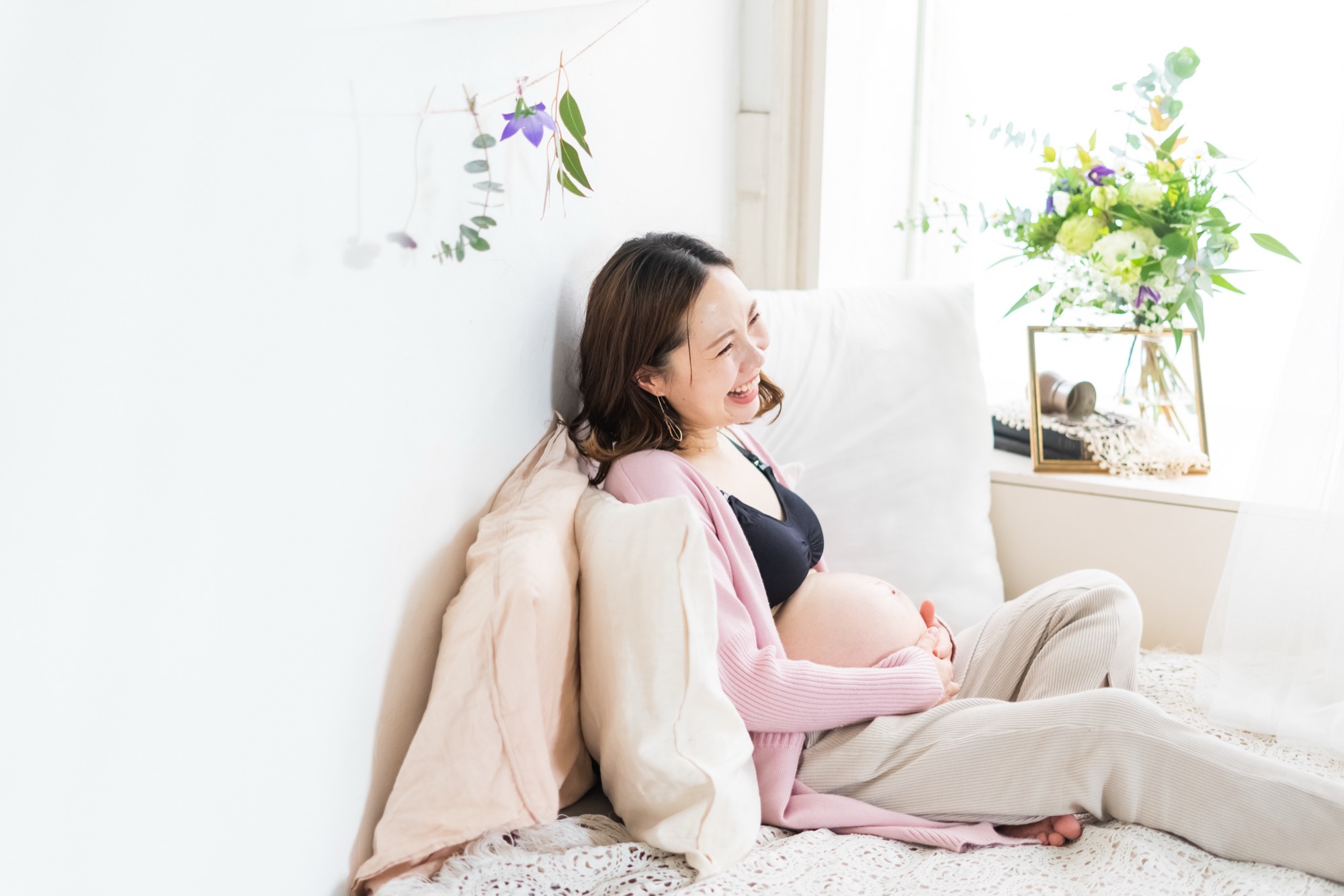 お腹に手を添えて笑う、妊娠中の女性