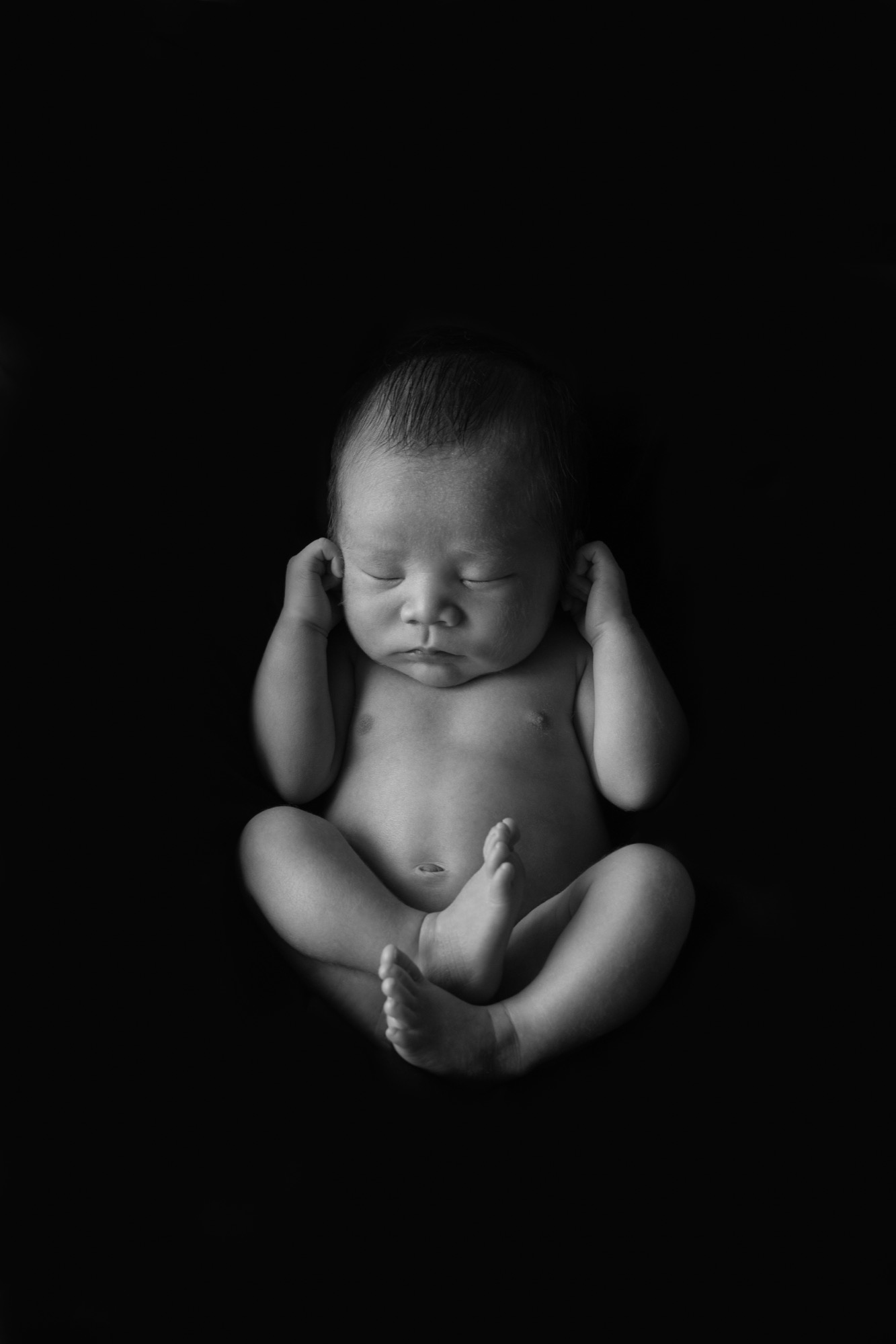 黒い背景に浮かび上がる、生まれたばかりの赤ちゃんのモノクロ写真