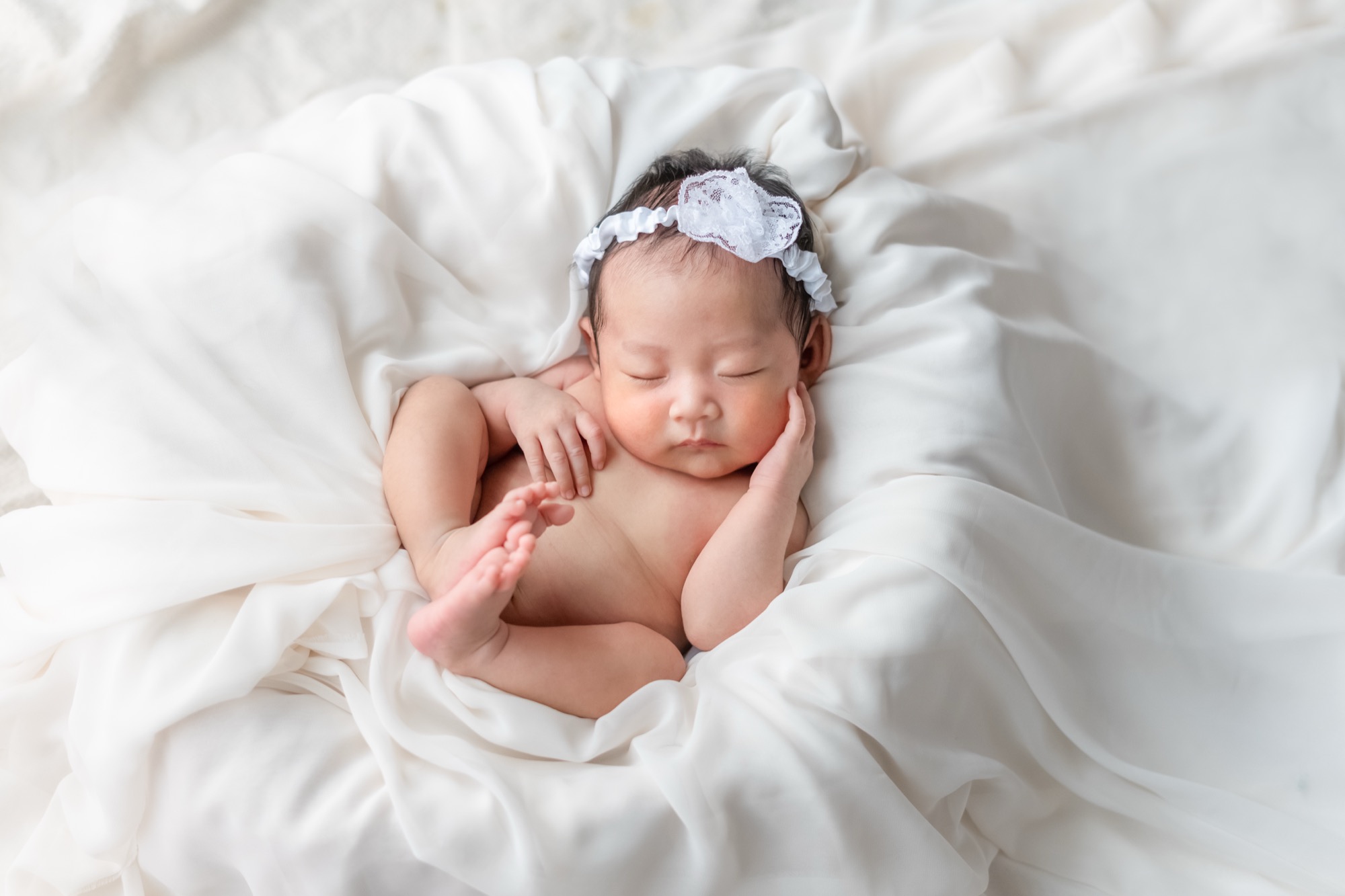 白い布に包まれて眠る新生児